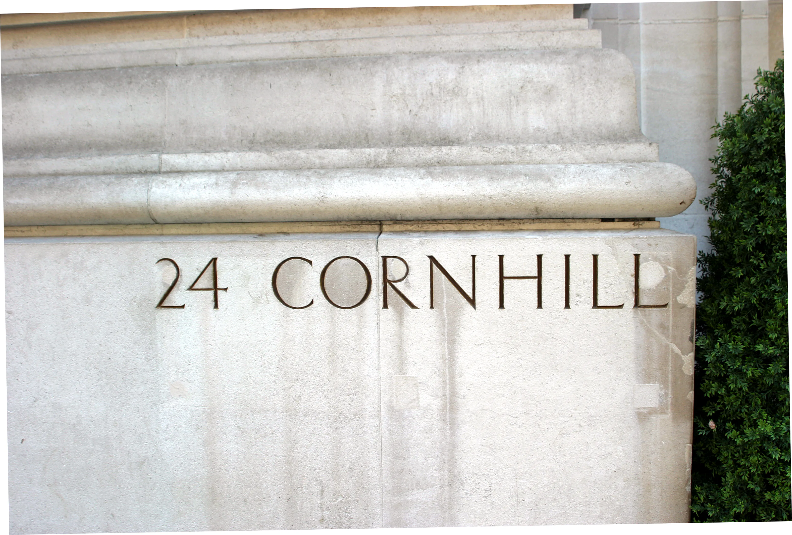 24 Cornhill cut into the building's stone facade, beside clipped greenery.