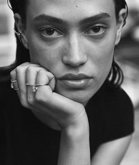 A close portrait in black and white, hand raised to the chin.