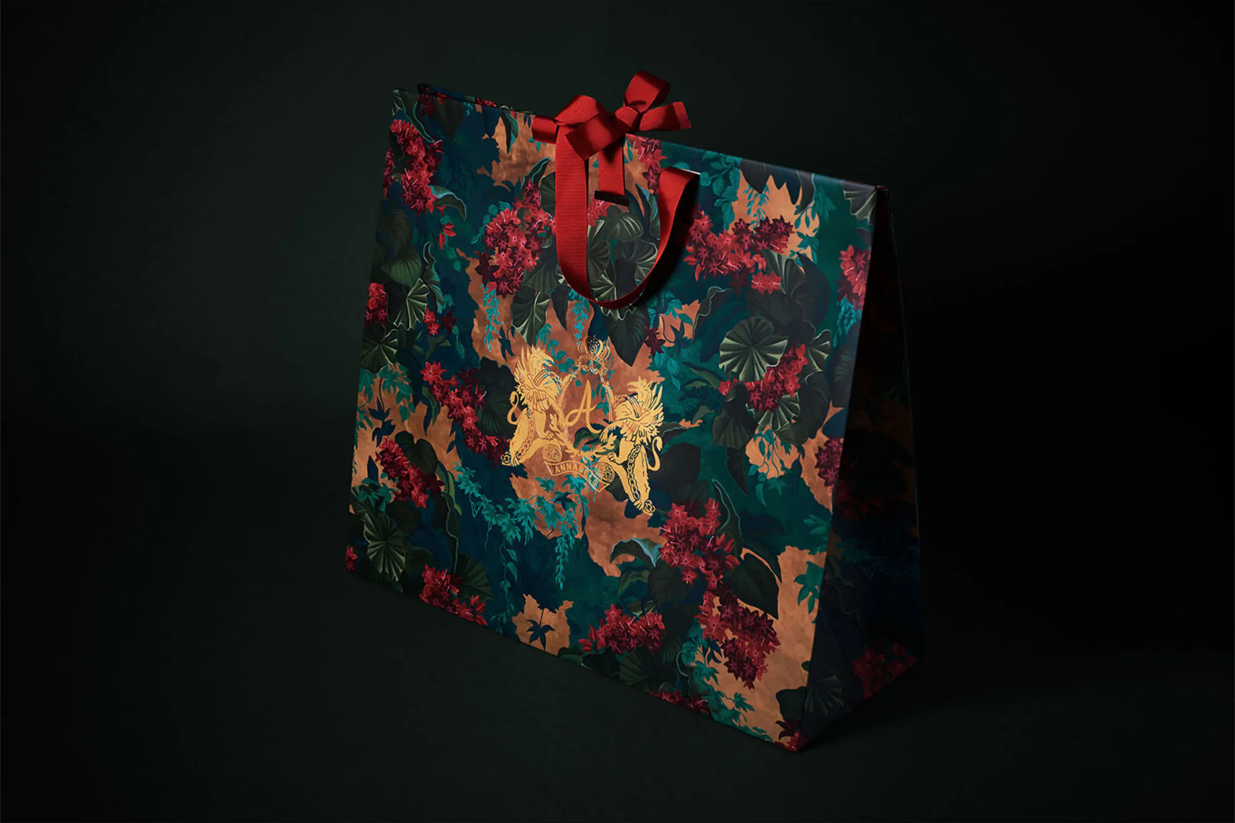 Annabel's carrier bag in the floral print, with red ribbon handles.