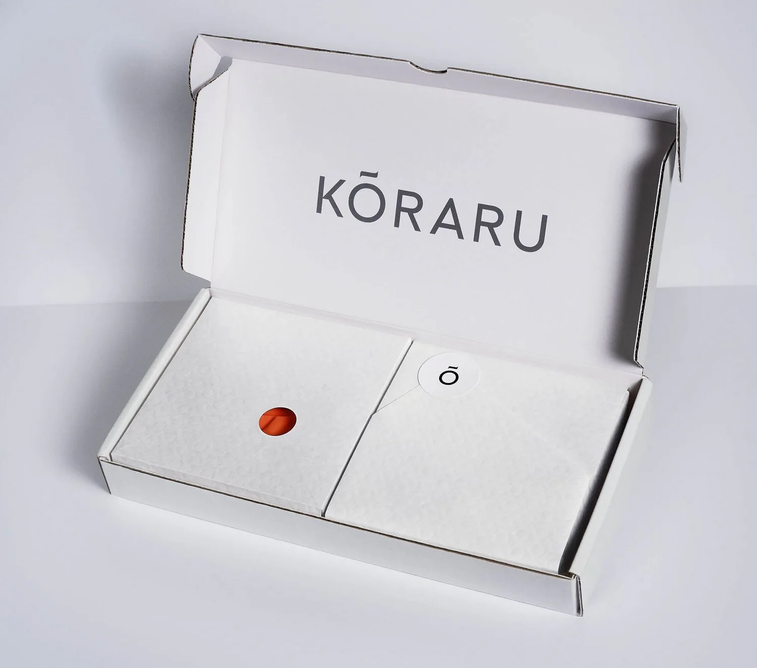 An open Koraru box divided in two, with a small red seal in the centre.