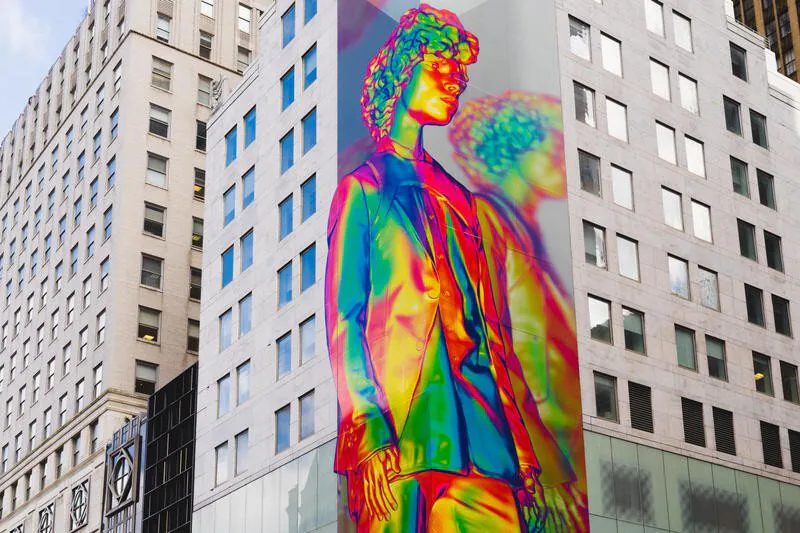 A giant holographic figure of a man standing between two city buildings.