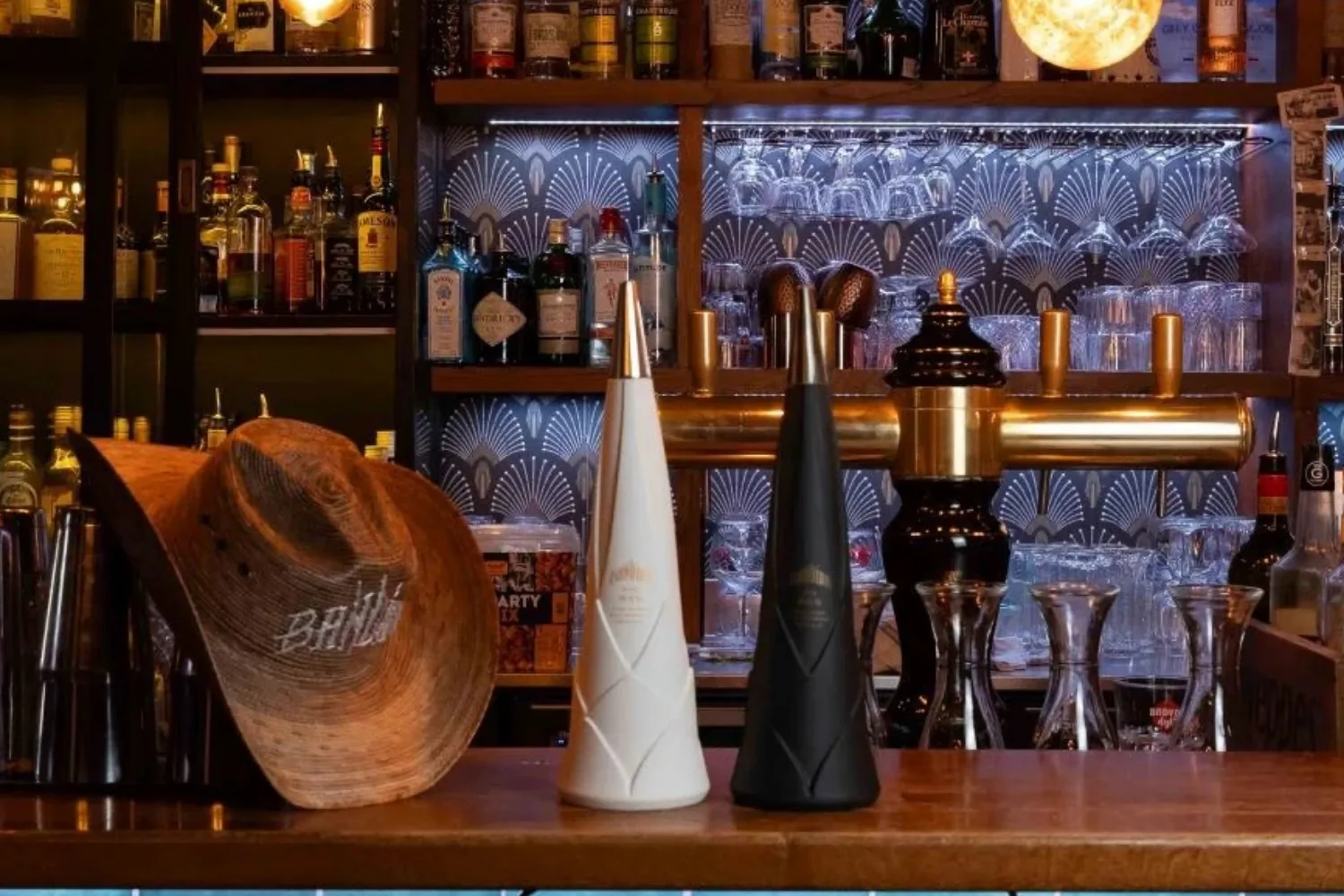 Two Bandida bottles and a hat on a lit back bar.