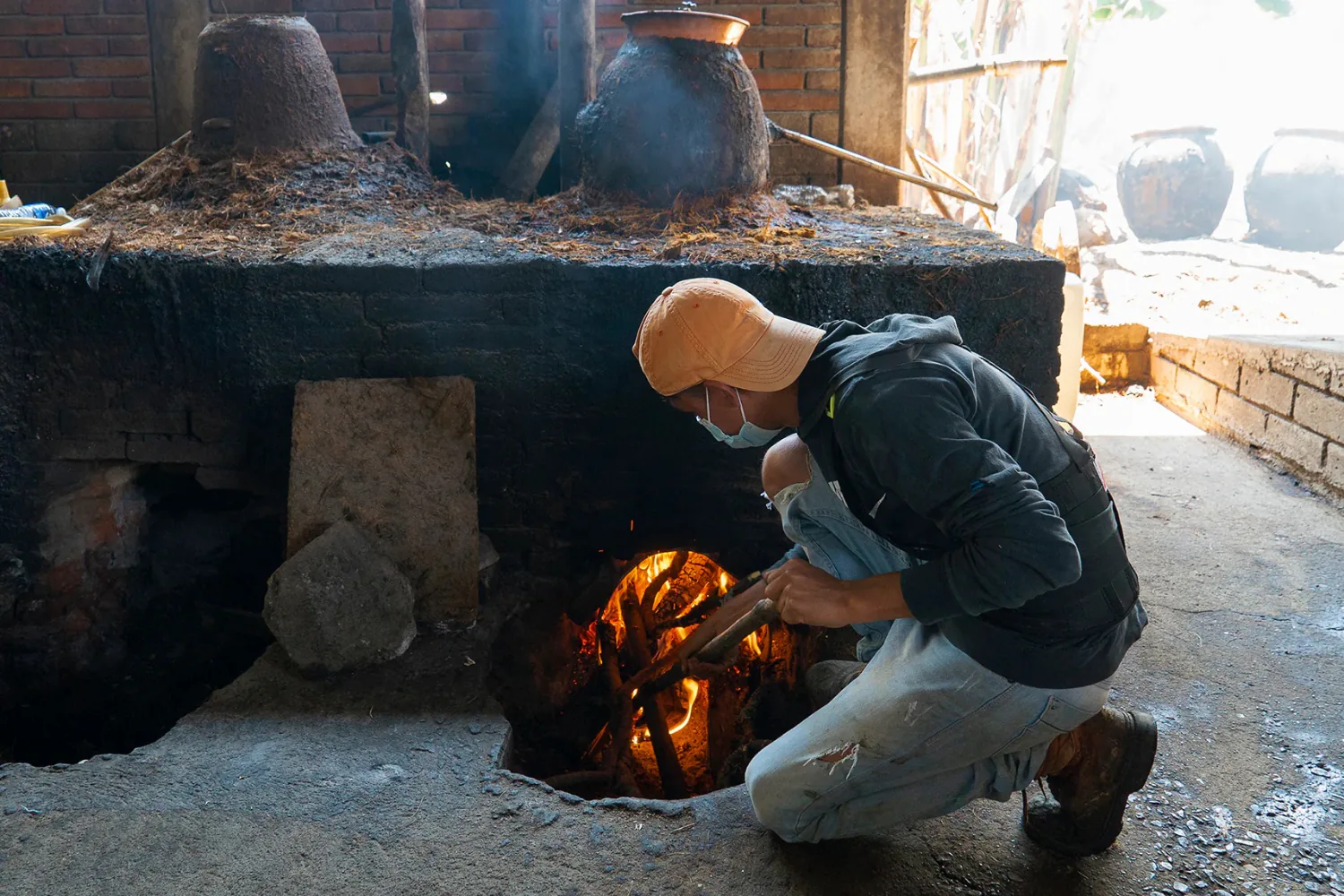 A mezcalero tending a fire pit at the palenque.