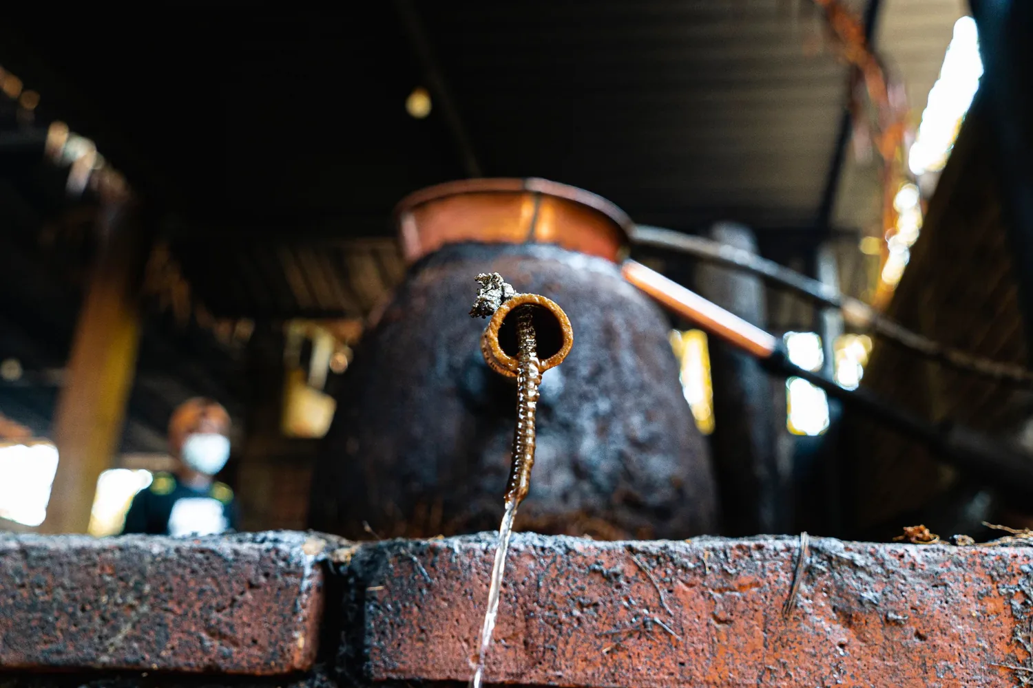 A copper still head above the brick furnace at the palenque.