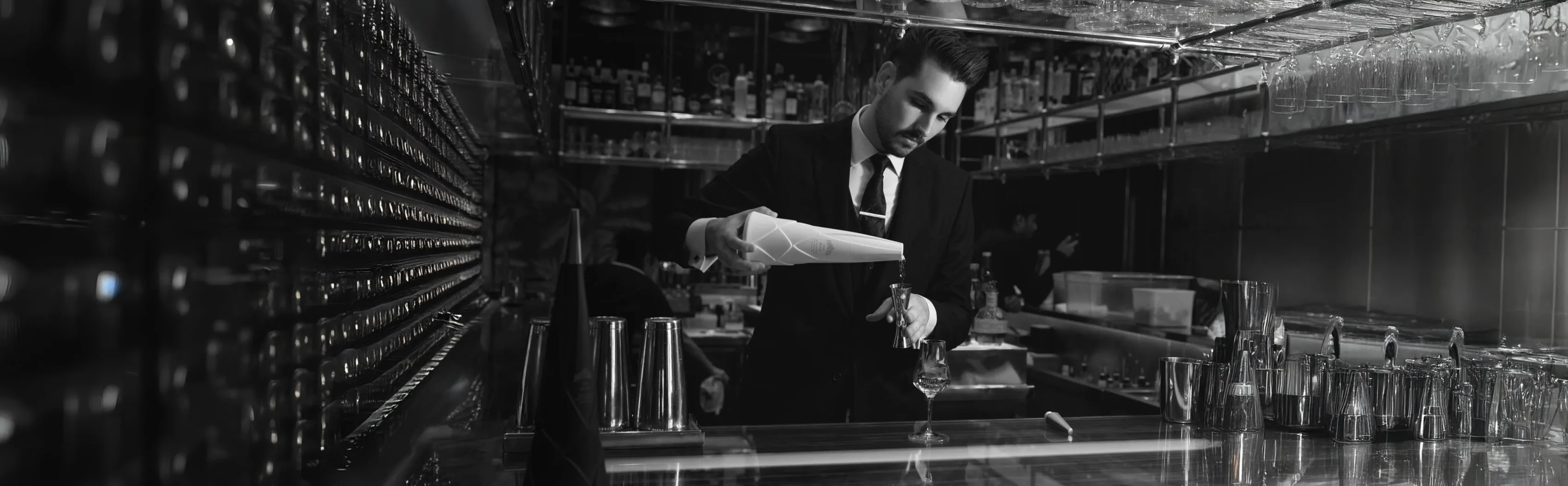 The same bartender at the back bar, in black and white, full width.