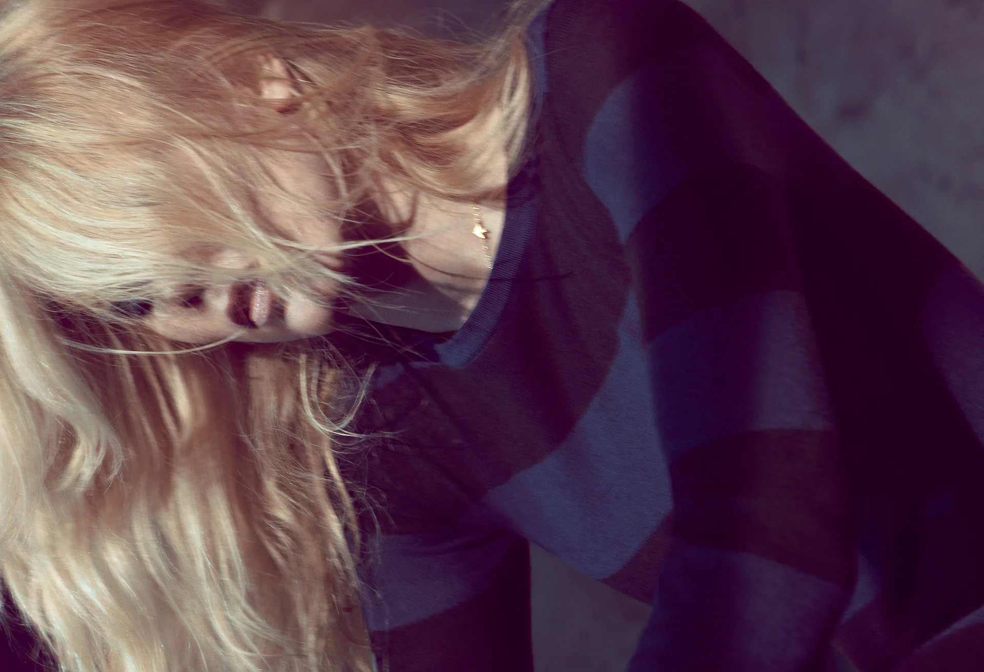 A close frame of blonde hair falling across a soft cashmere collar.
