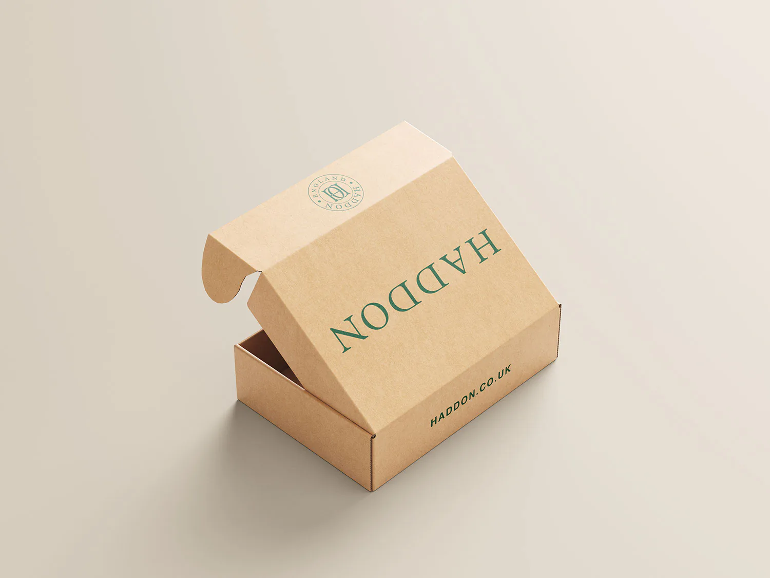 A kraft mailer box with its lid open, Haddon printed along the side.