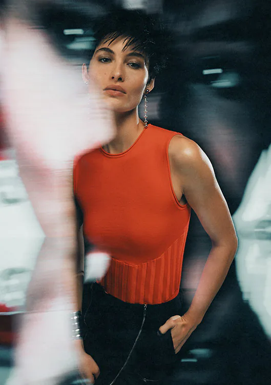 A model in an orange sleeveless top, the frame streaked with motion blur.