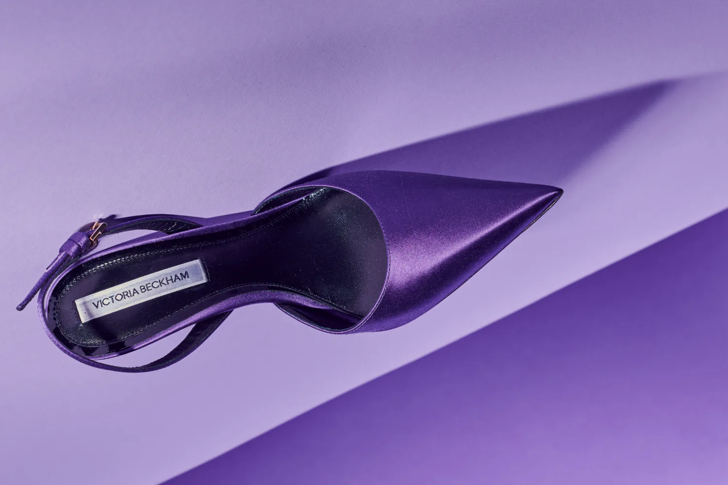 A purple satin slingback heel on a purple ground.