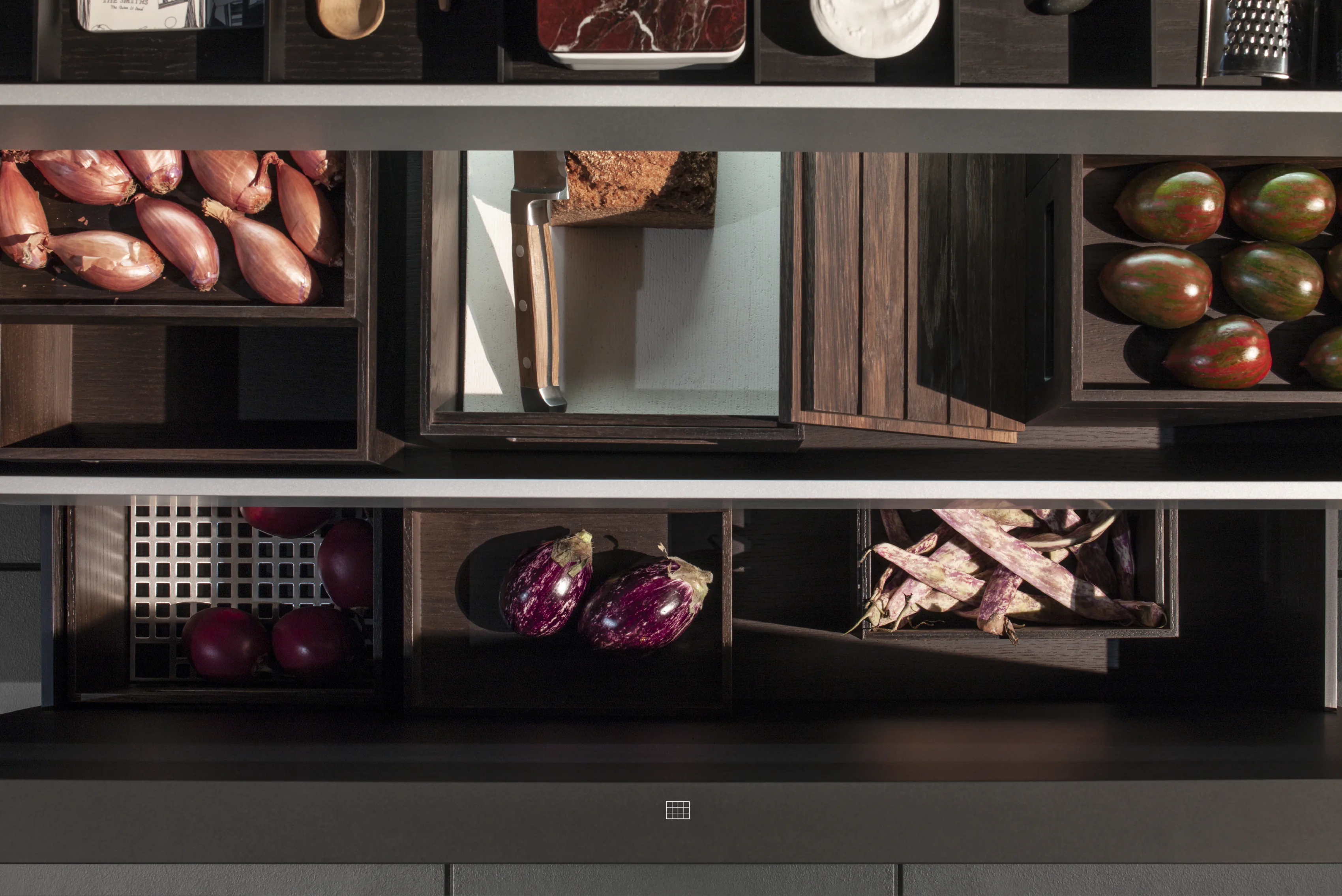 Open kitchen shelving in dark wood, each compartment holding vegetables and bread.