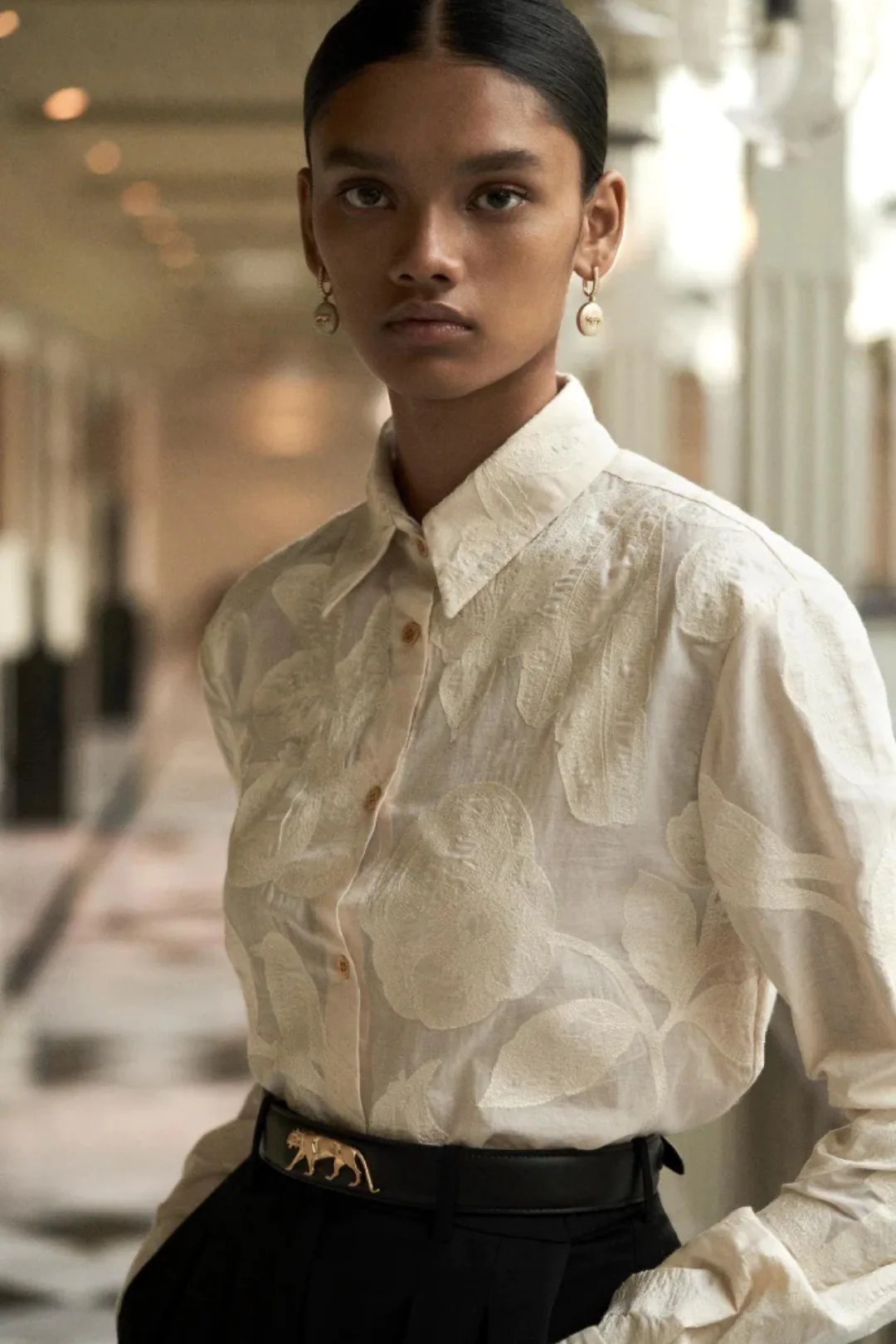 A model in an ivory jacquard shirt, in a colonnaded corridor.