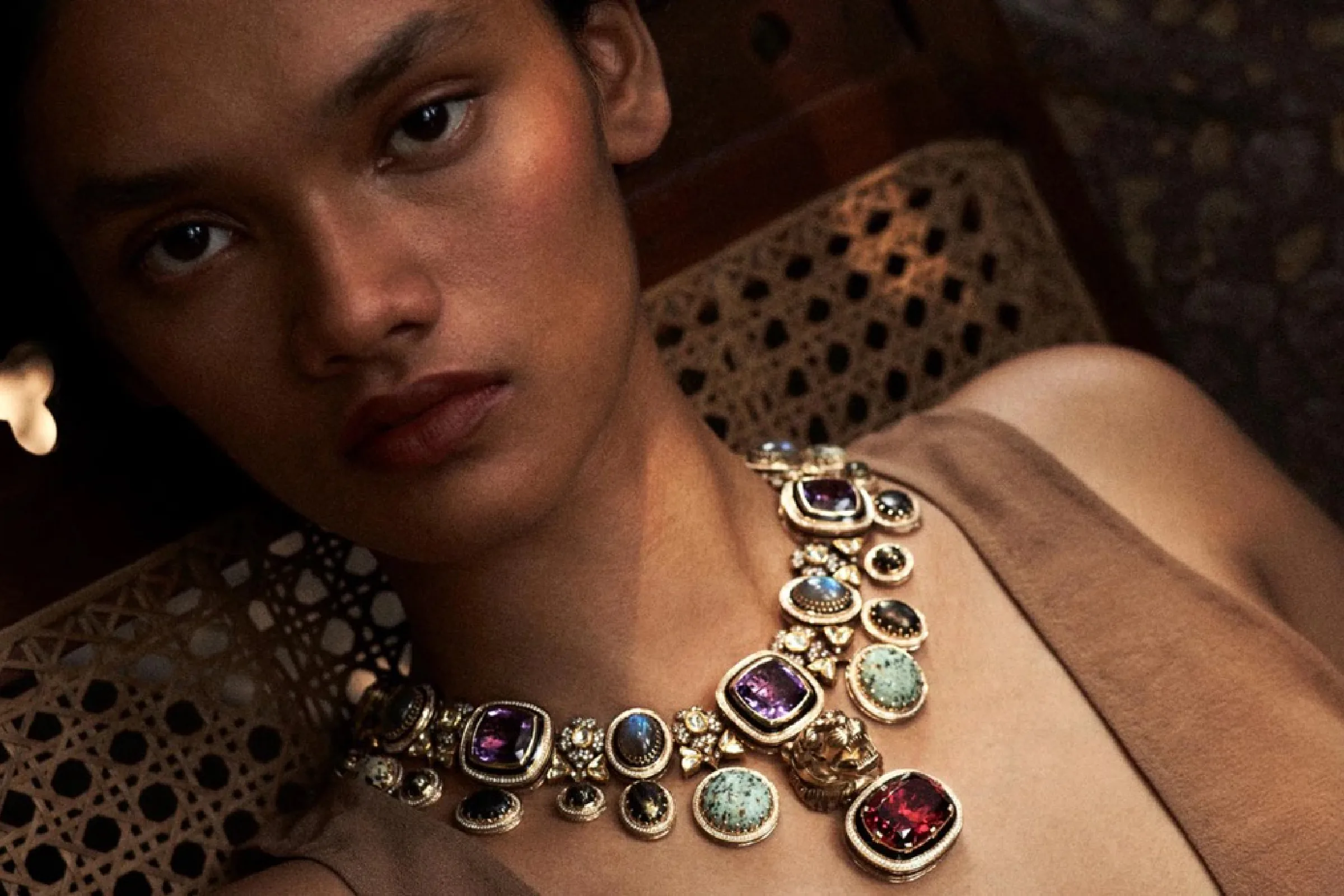 A model wearing a collar necklace set with coloured gemstones.