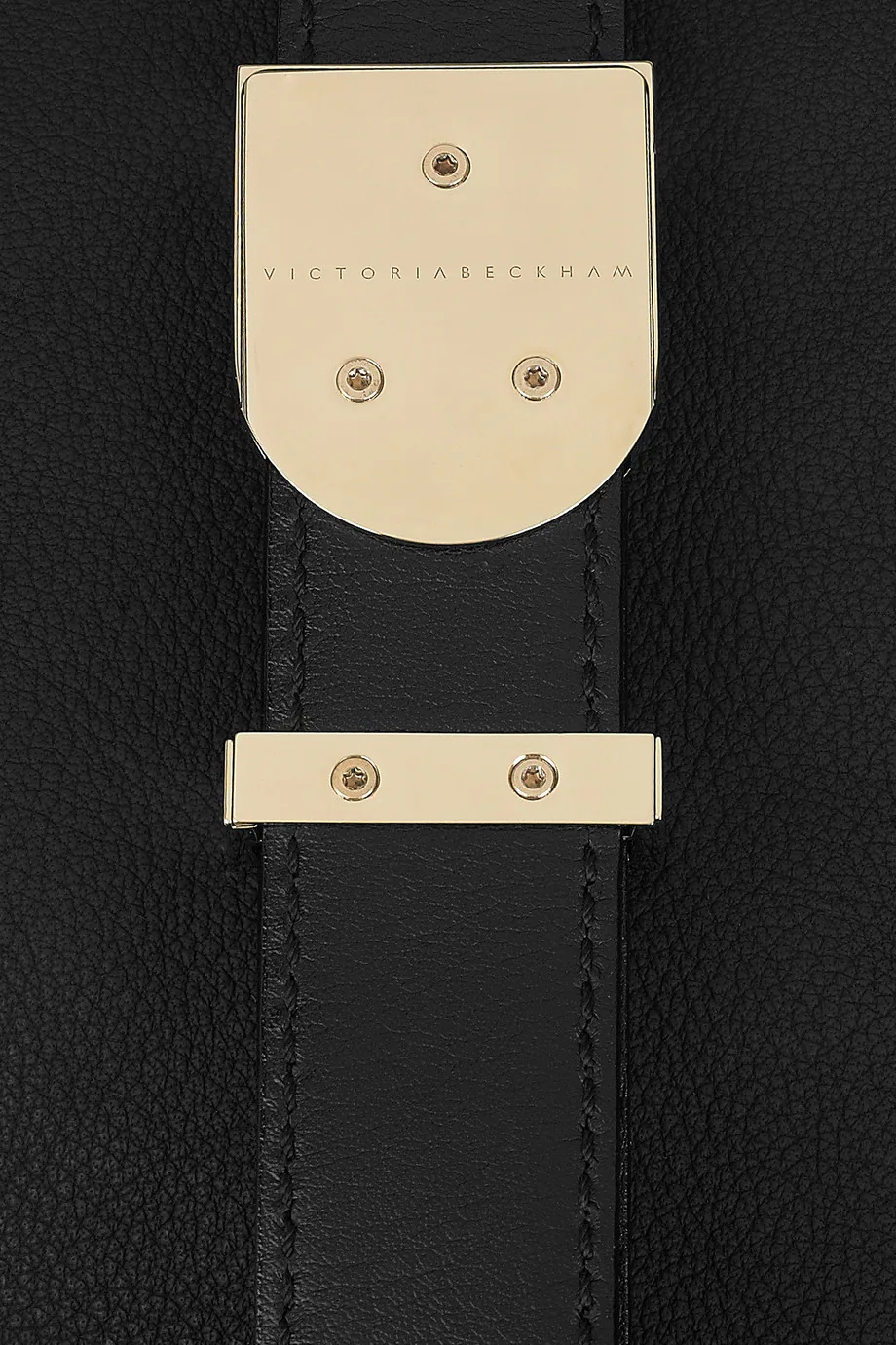 The strap and buckle of a leather bag, in close up.