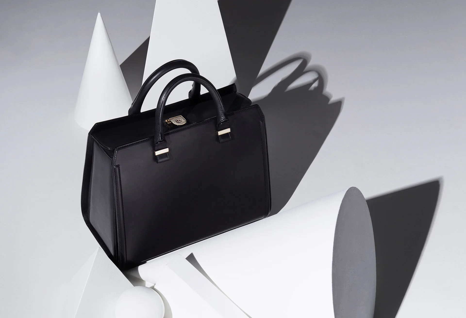 A black leather tote bag against a white ground.