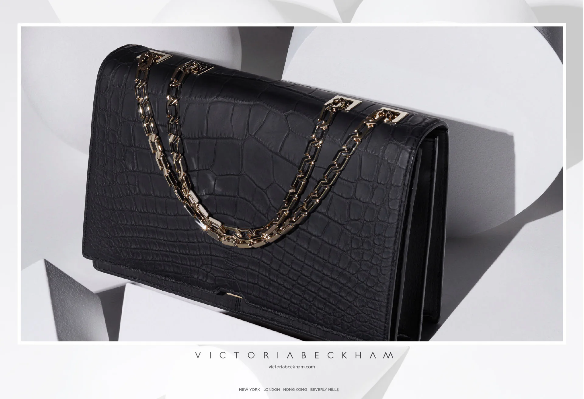 A black crocodile clutch bag with a chain handle.
